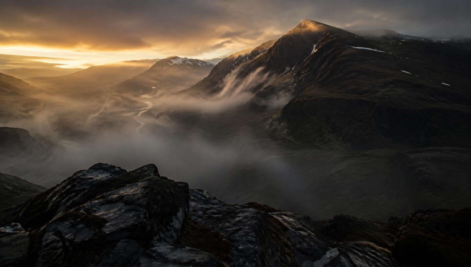 Scottish mountain ridge at sunrise with mist in the glen